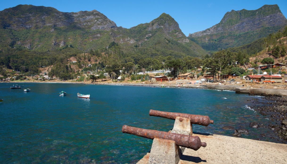 Cannoni presenti sull'isola di Robinson Crusoe in Cile, con villaggio sullo sfondo