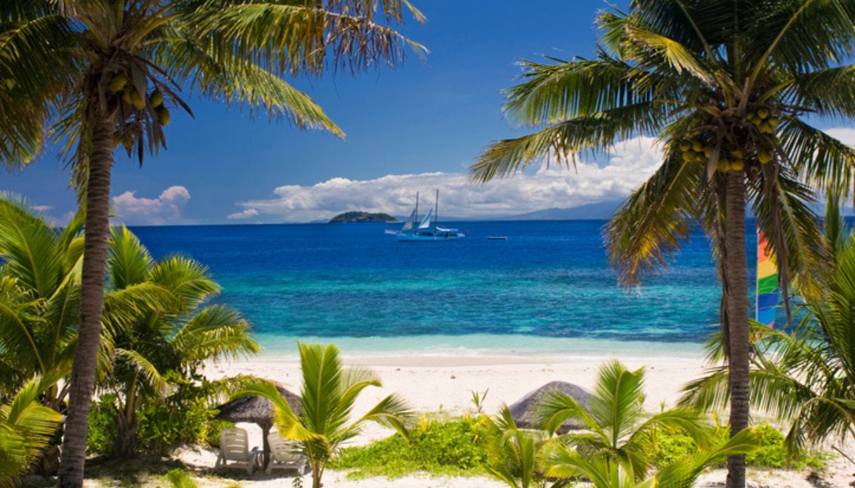 Spiaggia delle Isole Mamanuca, isole Fiji, con barca a vela e catamarano sullo sfondo