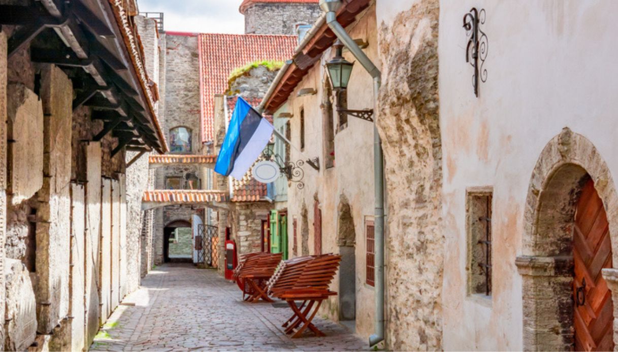 Scorcio del centro storico medievale di Tallinn, con la via acciottolata e la bandiera estone