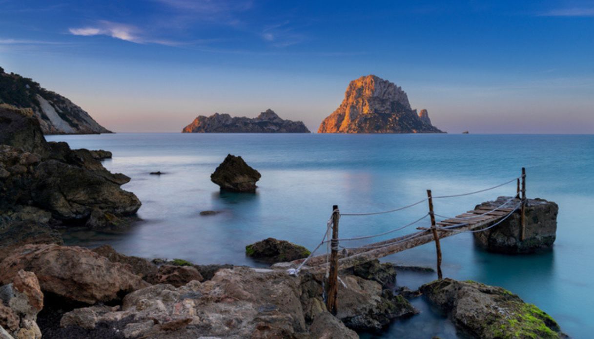 Piccolo pontile di legno a Cala d'Hort con vista sull'isolotto di Es Vedrà all'alba