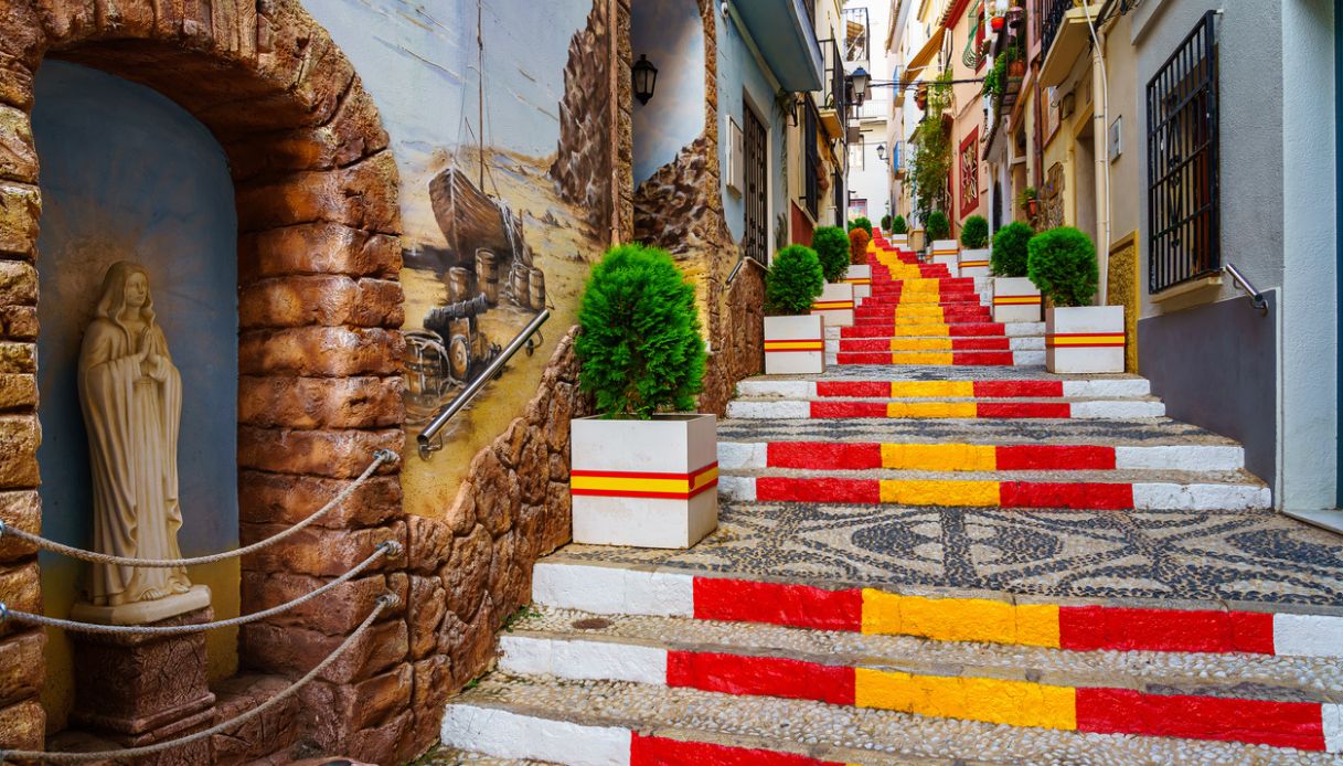 Via del centro storico di Calpe, in Spagna, con gradini colorati di giallo e rosso in onore della bandiera spagnola