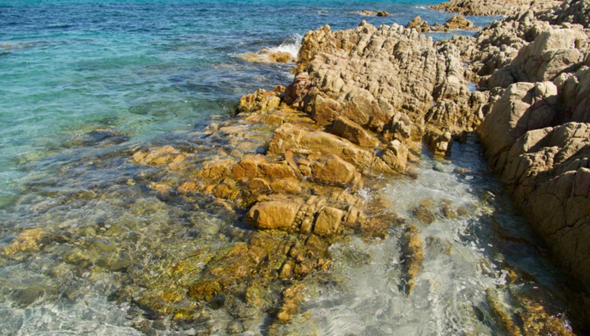 Mare cristallino a Cala Liberotto, con scogli quasi color oro in contrasto con azzurro del mare