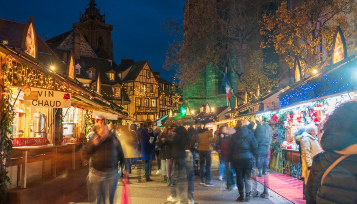 Mercatini di Natale a Colmar, in Francia, con stand e casette in legno e gente in strada