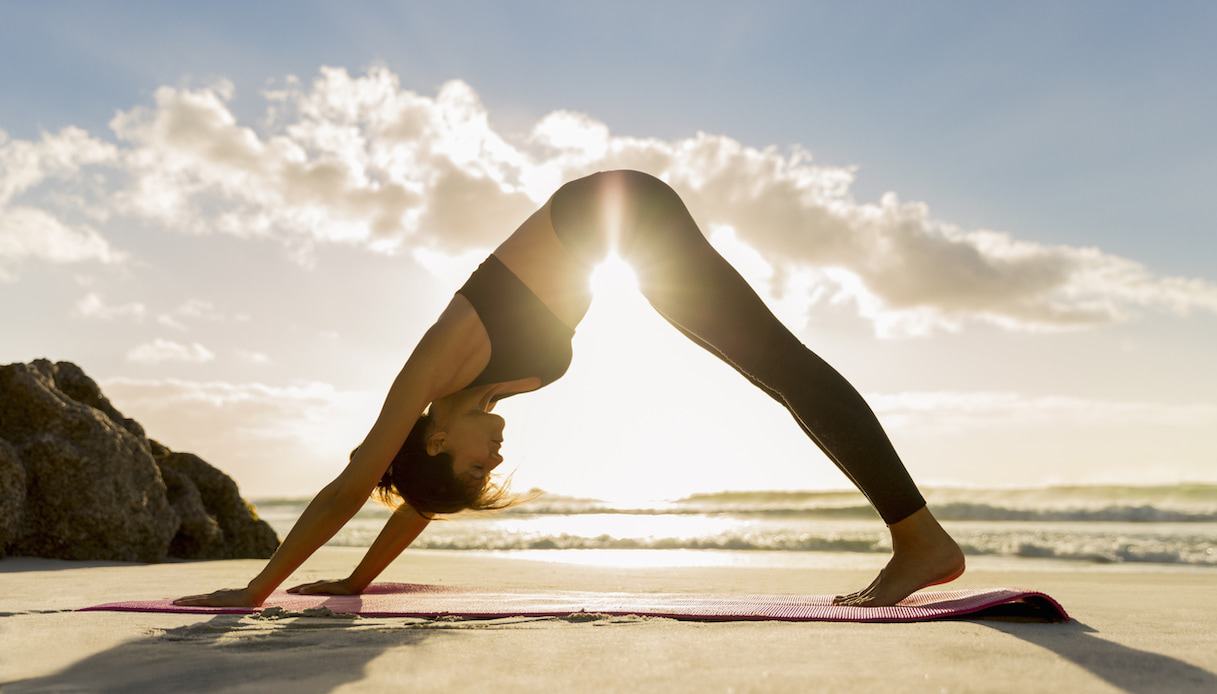 Donna che fa yoga in spiaggia