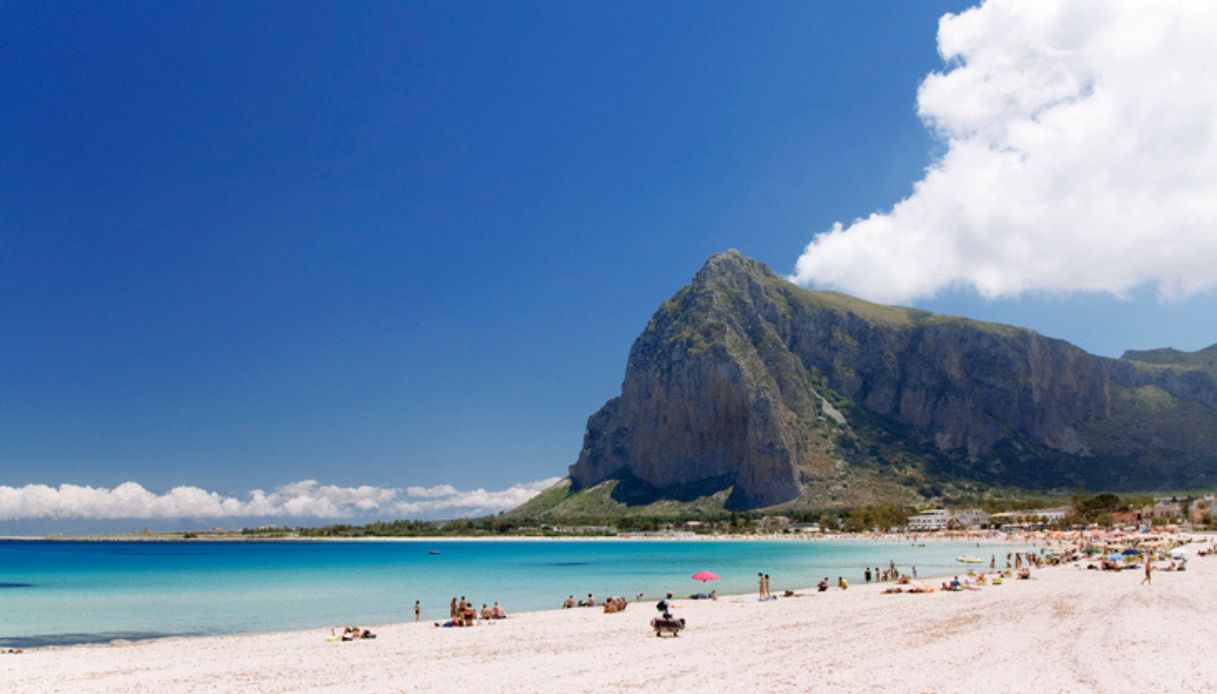 Vista della spiaggia di San Vito lo Capo in Sicilia, con la sabbia bianca in primo piano ed il promontorio sullo sfondo