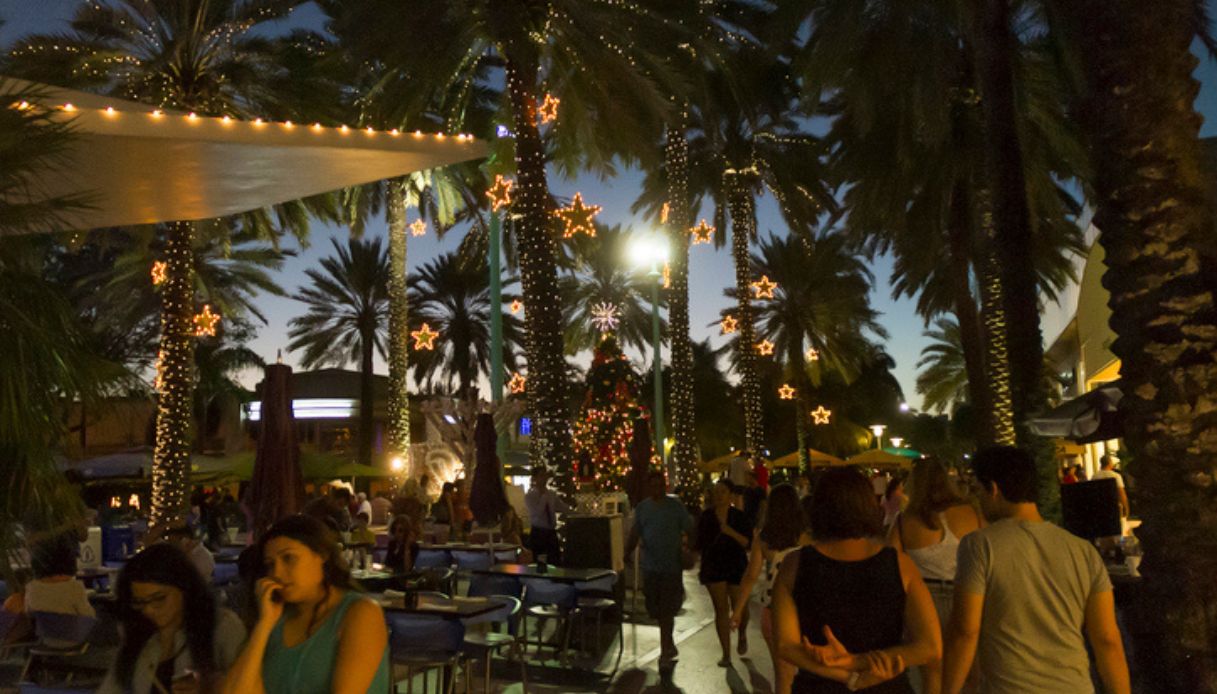 Gente che cammina a Miami a Natale con illuminazioni e addobbi sulle palme