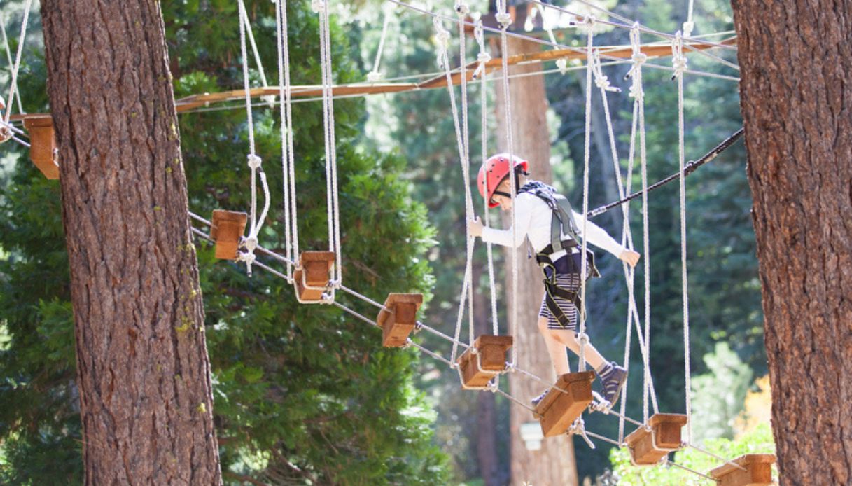 Bambino gioca su un ponte sospeso in un parco divertimenti della Valsugana