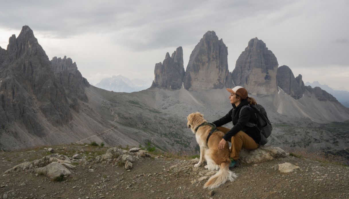 Cane con una ragazza dopo un escursione sulle montagne delle Dolomiti e con sullo sfondo le Tre Cime di Lavaredo