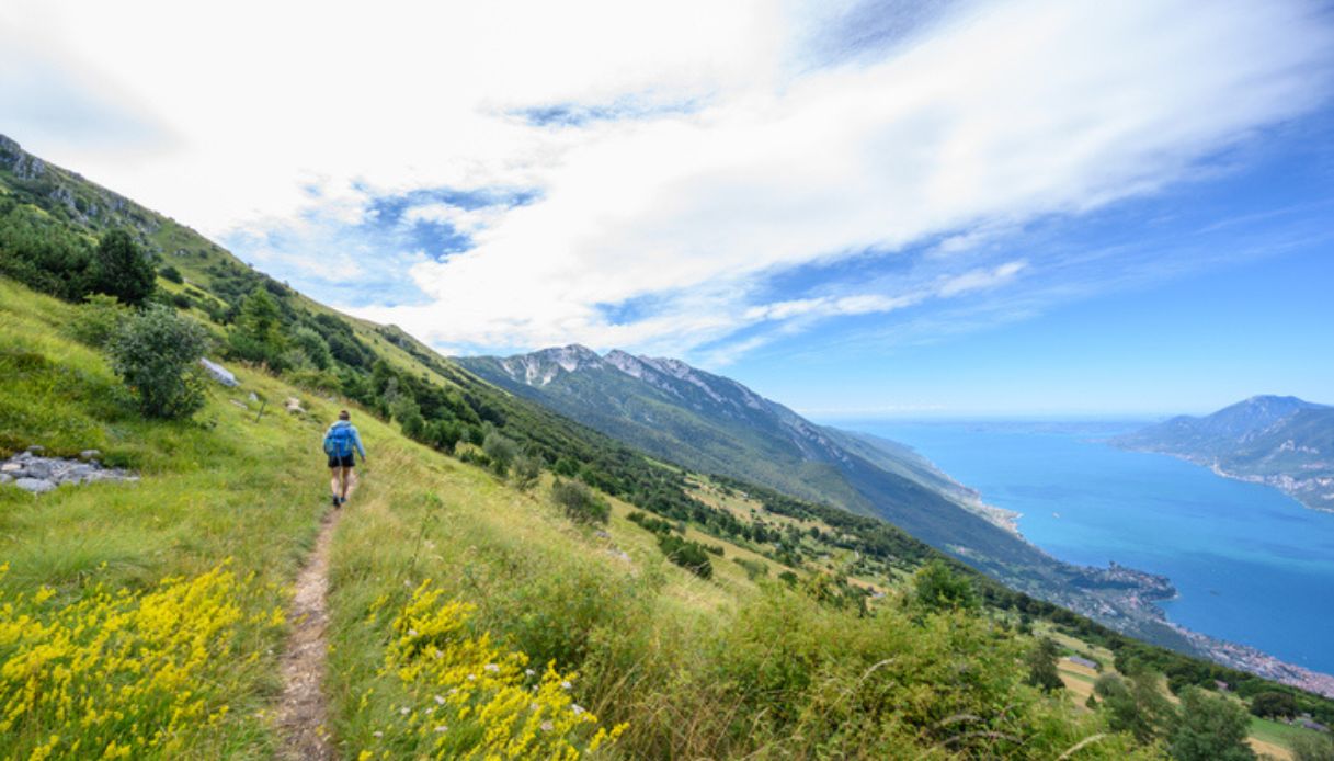 Uomo percorre il Sentiero del Monte Baldo con il lago di Garda sullo Sfondo