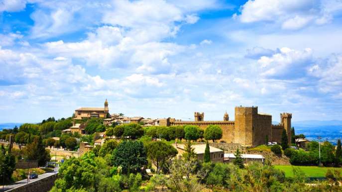 Castelli della Val d’Orcia che si stagliano tra cipressi, colline e cieli infuocati