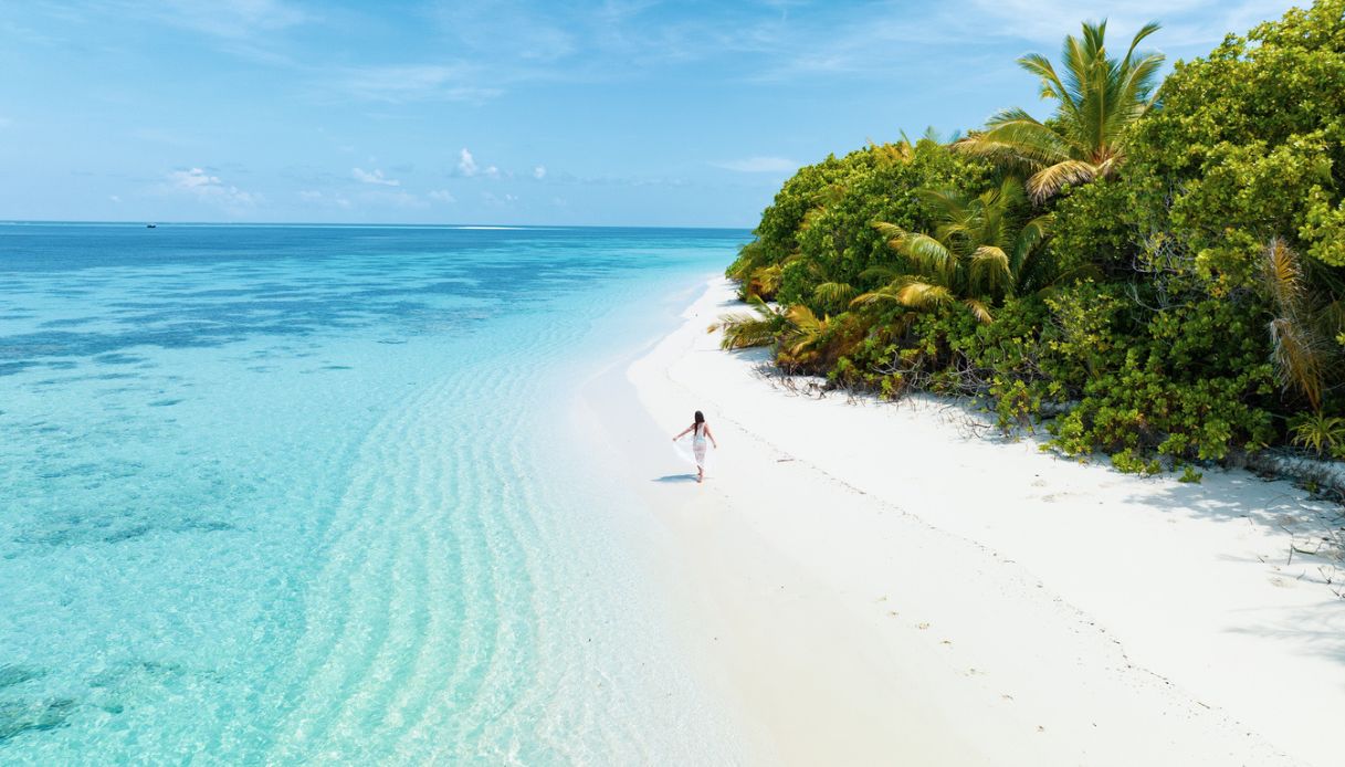 Vista aerea del drone di una donna che cammina sull'isola deserta alle Maldive