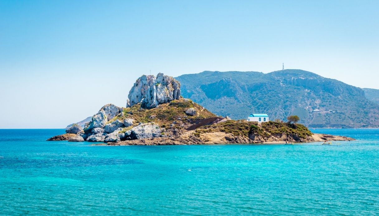 Vista panoramica dell'isola di Kastri con cappella di Agios Nikolas dalla spiaggia di Agios Stefanos sull'isola di Kos