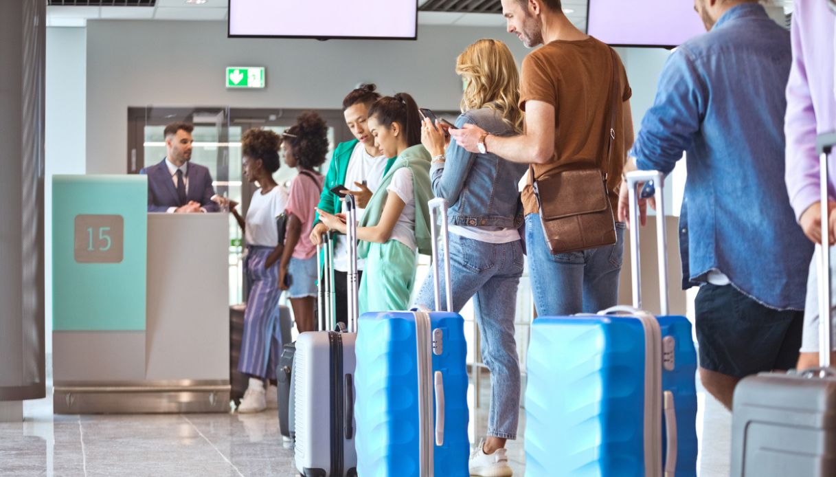 Passeggeri con bagagli in attesa in fila in aeroporto