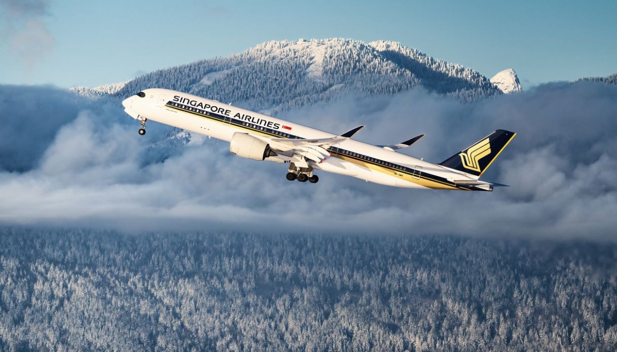 Aereo Singapore Airlines in decollo su un paesaggio montano innevato