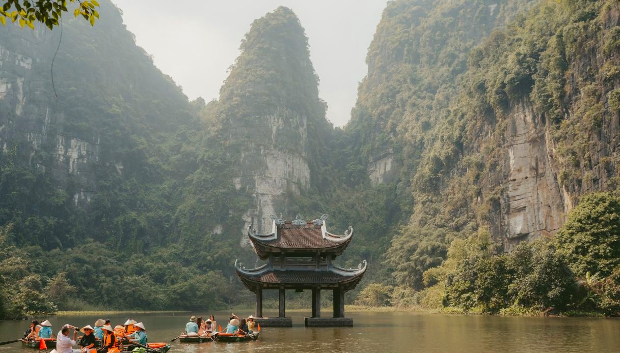 Barche a remi con turisti tra le montagne carsiche di Trang An, a Ninh Binh, nel Vietnam del Nord
